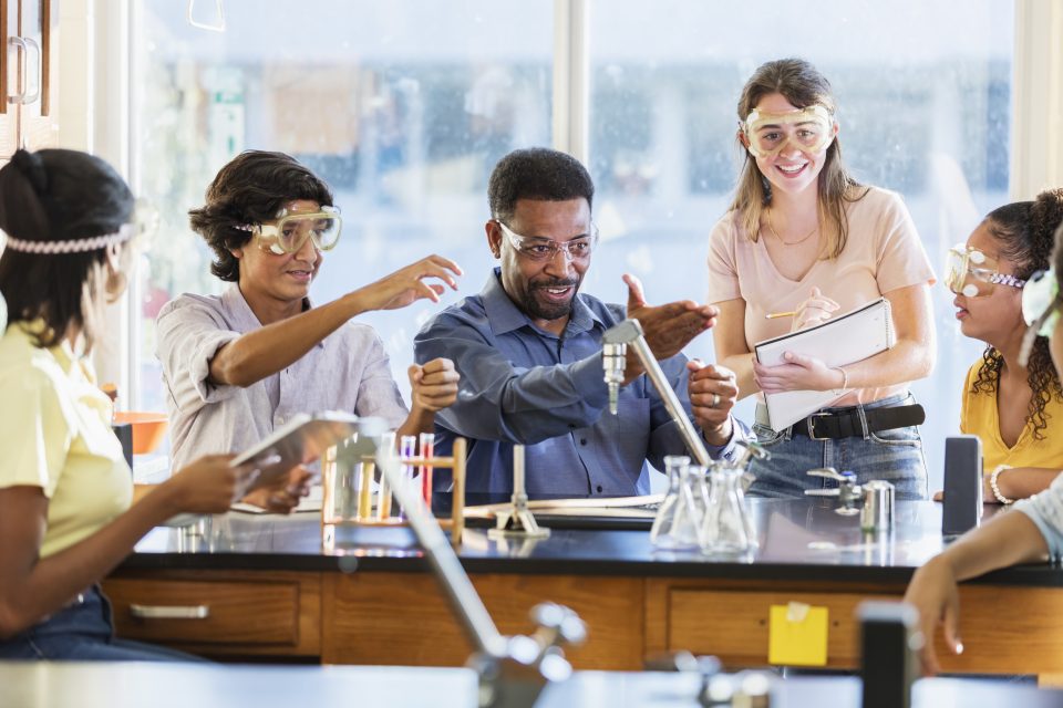 Hombre afroamericano enseñando laboratorio de química de secundaria